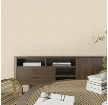 Pokoj se světlou strukturovanou tapetou, tmavým dřevěným příborníkem a stolem s ratanovým výpletem ve světlém interiéru.