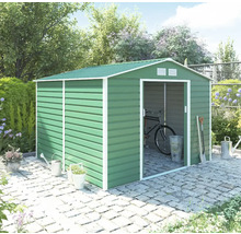 Zelený kovový zahradní domek se sedlovou střechou a posuvnými dveřmi na dlažbě v zahradě, s jízdním kolem uvnitř a zahradním nářadím venku.