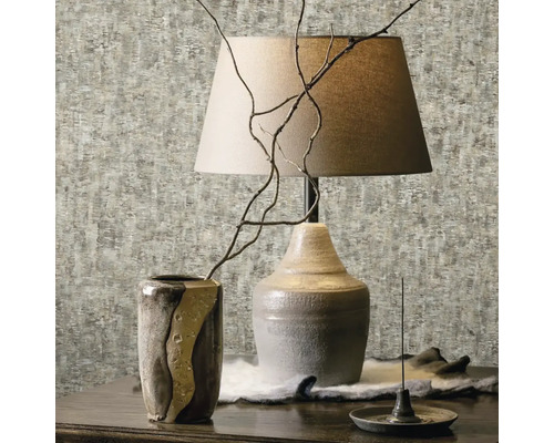 Strukturovaná tapeta se vzhledem kamene a textilu v místnosti se stolní lampou, keramickou vázou a větvemi v přírodním stylu.