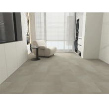 Velkoformátová dlažba ve světle šedé barvě, moderní obývací prostor s bílým křeslem, odkládacím stolkem a oknem, světlý a prostorný pokoj.