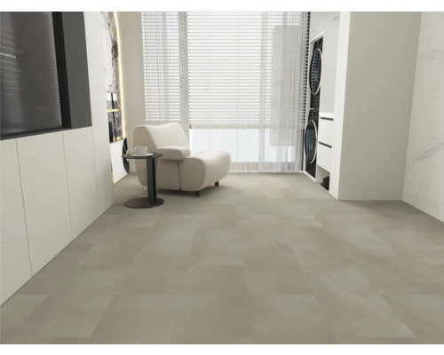 Velkoformátová dlažba ve světle šedé barvě, moderní obývací prostor s bílým křeslem, odkládacím stolkem a oknem, světlý a prostorný pokoj.