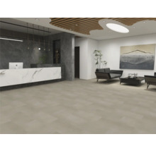 Moderně řešená recepce s velkoformátovou béžovou dlažbou, pultem s mramorovým efektem a posezením s tmavými pohovkami.