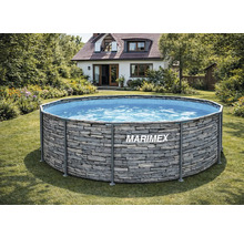 Kulatý bazén Marimex s kovovým rámem a vnějším dekorem kamene na trávníku v prosvětlené zahradě s domem v pozadí.