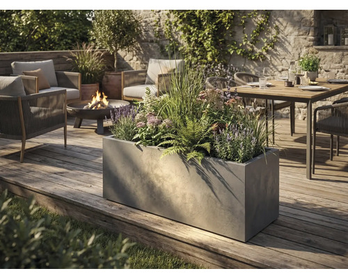 Velký obdélníkový květináč v betonovém vzhledu na dřevěné terase v moderně navržené zahradě s posezením a ohništěm.