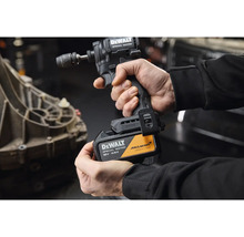 Osoba drží rázový utahovák DeWalt Special Edition s 18 voltovým 4 ampérhodinovým akumulátorem, DeWalt Logo a McLaren Formula 1 Team Logo.