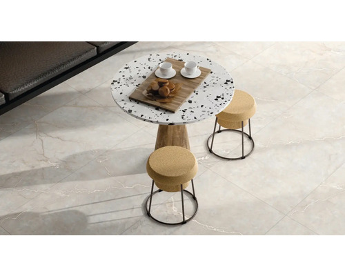 Moderní obývací pokoj s dlažbou v mramorovém vzhledu, kulatým terazzovým stolem a stoličkami s korkovým sedákem.