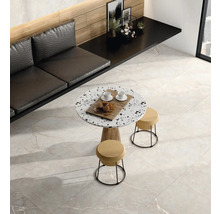 Moderní místnost se světle šedou dlažbou v dekoru mramoru, kulatým terazzo stolem se stoličkami a černou lavicí u dřevěné stěny.