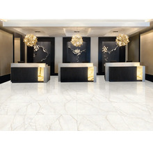 Moderní recepce s velkoformátovou dlažbou ve vzhledu bílého mramoru, třemi tmavými pulty a kulatými závěsnými svítidly.