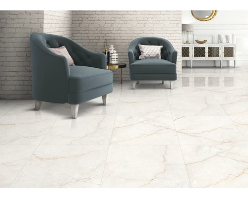 Světlý obývací pokoj se dvěma modrými křesly na velkoformátové dlažbě s mramorovým efektem a hnědým žilkováním u bílé cihlové stěny.