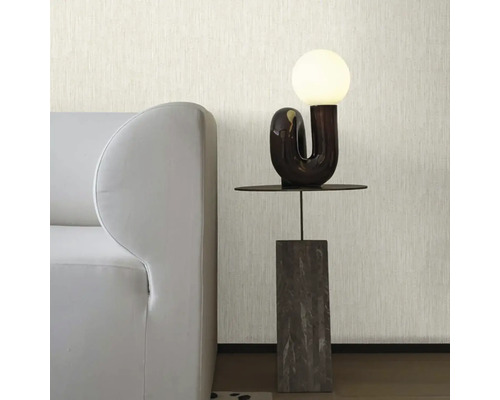 Moderní obývací pokoj se světlou strukturovanou tapetou, šedou pohovkou a designovou stolní lampou na minimalistickém stolku.