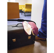 Černá brašna na nářadí s červenými návleky na obuv ve světlé místnosti se žlutými křesly a osobou v modrých pracovních kalhotách.