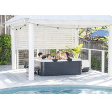 Rodina ve vířivce pod světlým pavilonem na dřevěné terase u bazénu se světelným řetězem.