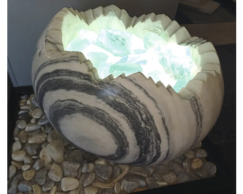 Dekorativní lampa ve tvaru rozbitého vejce z mramorovaného kamene, plněná svítícími skleněnými kameny na oblázcích.