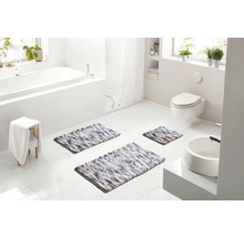 Světlá koupelna s vanou, toaletou a umyvadlem, vybavená třemi vícebarevnými koupelnovými předložkami různých velikostí.