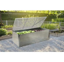 Kovový vyvýšený záhon s otevřeným průhledným víkem a rostlinami salátu v zahradě.