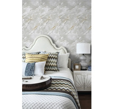 Světlá ložnice s tapetou ve vzhledu mramoru, postelí s čelem a ozdobnými polštáři a nočním stolkem s dekorativní stolní lampou.