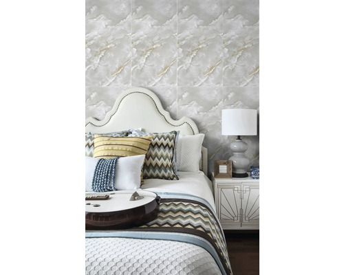 Světlá ložnice s tapetou ve vzhledu mramoru, postelí s čelem a ozdobnými polštáři a nočním stolkem s dekorativní stolní lampou.