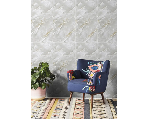 Obklad v imitaci mramoru ve světlé místnosti s modrým křeslem a pokojovou rostlinou.