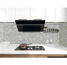 Moderní světlá kuchyně s černou digestoří, plynovou varnou deskou na bílé mramorové pracovní desce a obkladem v dekoru mramoru s náčiním.