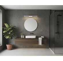 Moderní koupelna s kulatým zrcadlem, lineárním LED nástěnným svítidlem, závěsnou dřevěnou skříňkou pod umyvadlo, bílým umyvadlem na desku a sprchou.