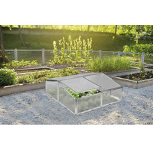 Malé pařeniště z hliníku a plastových desek v organizované zahradě s vyvýšenými záhony na štěrku.