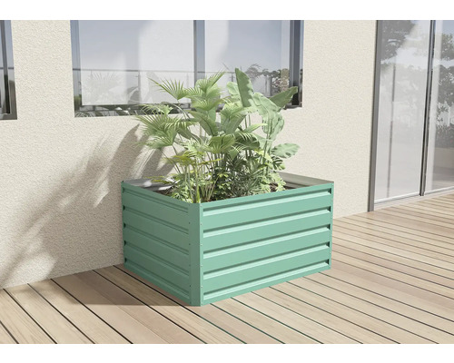 Kovový vyvýšený záhon s rostlinami na dřevěné terase u stěny domu.