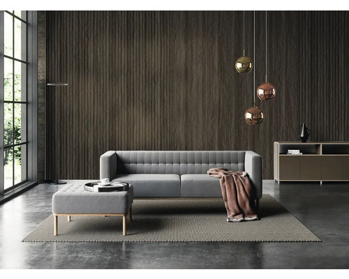 Moderní obývací pokoj s tmavě hnědým obkladem stěn s lamelovým efektem, šedou pohovkou, taburetem a kulatými kovovými závěsnými svítidly.