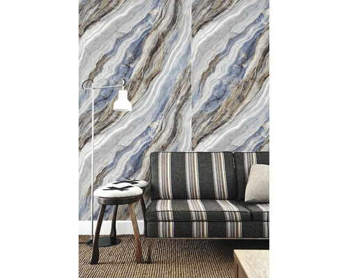 Vliesová tapeta s diagonálním mramorovým vzorem v modré a šedé barvě za pruhovanou pohovkou a stojací lampou v obývacím pokoji.