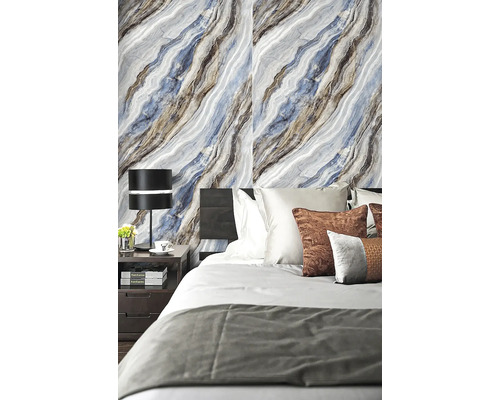 Moderní ložnice se stěnou ve vzhledu mramoru, tmavou postelí a nočním stolkem s černou stolní lampou.