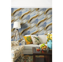 Obývací pokoj s abstraktní tapetou ve zlaté a modré barvě, světlou pohovkou s dekorativními polštáři a stojací lampou.