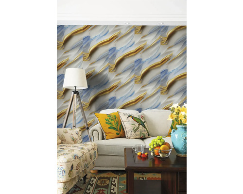 Obývací pokoj s abstraktní tapetou ve zlaté a modré barvě, světlou pohovkou s dekorativními polštáři a stojací lampou.