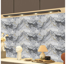 Mramorovaná nástěnná dekorace v šedé a bílé s černým LED osvětlením pod skříňkou nad odkládací plochou s dekoracemi a lampičkou.