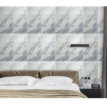 Obklady s mramorovým vzhledem za postelí v ložnici, v kombinaci s nástěnným svítidlem a koženým čelem postele.