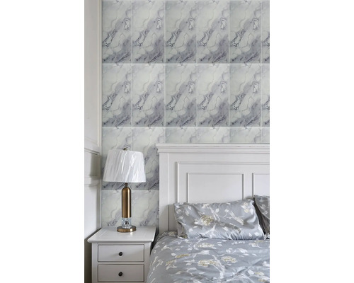 Obklady na stěnu s mramorovým vzhledem ve světlé ložnici s bílou postelí a nočním stolkem.