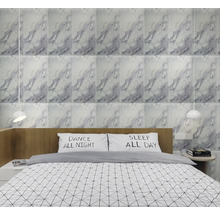 Nástěnné obklady s šedo-bílým mramorovým vzorem ve světlé, moderní ložnici s dřevěným čelem postele a dvěma bílými závěsnými lampami.