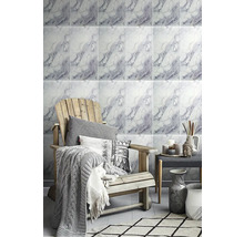 Moderní obývací pokoj se stěnou v mramorovém vzhledu, dřevěné křeslo s dekou a polštáři, dekorativní vázy a odkládací stolek.