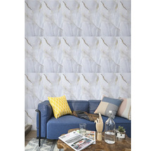 Obklad v mramorovém vzhledu na stěně za modrou pohovkou s polštáři a dekou. Před ní je malý konferenční stolek.