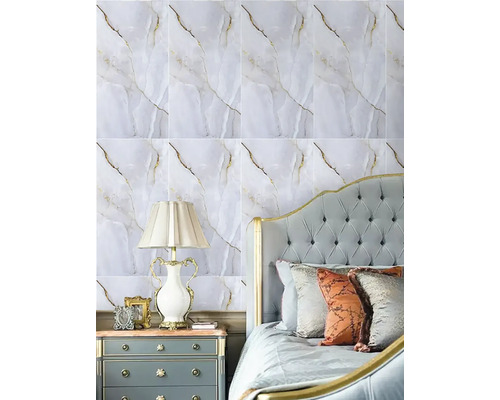 Ložnice s tapetou ve vzhledu mramoru se zlatými žilkami, prošívaným čelem postele, nočním stolkem a klasickou stolní lampou.