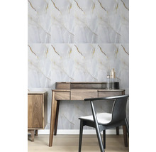 Světlý pracovní prostor s nástěnnými panely ve vzhledu mramoru se zlatými žilkami, stolem z tmavého dřeva a černou židlí.