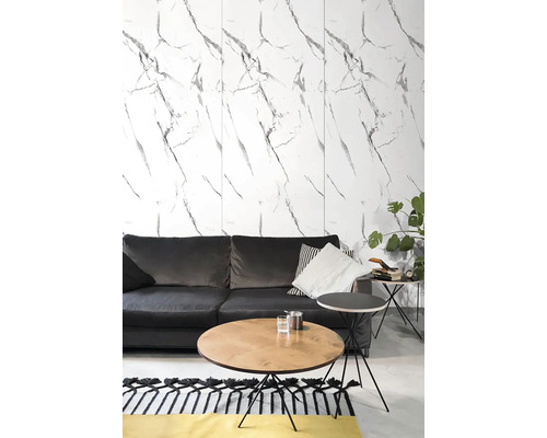 Moderní obývací pokoj s nástěnnými panely v mramorovém vzhledu, tmavě šedou pohovkou, kulatým dřevěným stolkem a černým odkládacím stolkem.