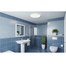 Moderní koupelna s nástěnnými dlaždicemi, sloupovým umyvadlem, zrcadlem, sprchovým koutem se skleněnou stěnou a závěsnou toaletou.