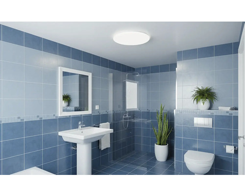 Moderní koupelna s nástěnnými dlaždicemi, sloupovým umyvadlem, zrcadlem, sprchovým koutem se skleněnou stěnou a závěsnou toaletou.