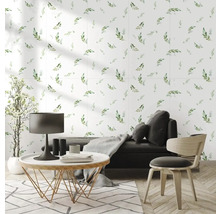 Moderní, světlý obývací pokoj s tapetou s motivem listů, tmavou pohovkou, kulatým konferenčním stolkem a parketami ve vzoru rybí kosti.