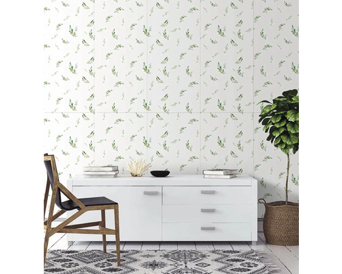 Světlé nástěnné obklady se vzorem zelených listů za bílou komodou v moderním, uklizeném obývacím pokoji s dřevěnou židlí a pokojovou rostlinou.