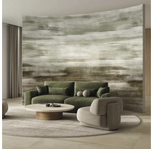 Abstraktní fototapeta s vodorovnými tahy štětcem v zemních tónech, doplněná zelenou pohovkou, šedým křeslem a kulatým konferenčním stolkem.