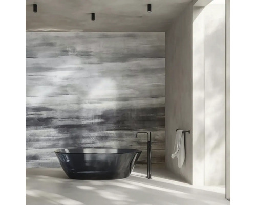 Moderní koupelna s volně stojící černou vanou, podlahovou baterií a strukturovanou akcentní stěnou v šedé barvě.