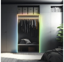LED pásek na šatní skříni v uspořádané ložnici. Vícebarevné osvětlení rámu skříně.