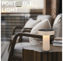 Přenosná LED stolní lampa se solárním panelem na dřevěném odkládacím stolku v útulném venkovním prostředí na terase.
