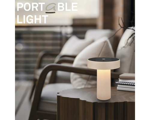 Přenosná LED stolní lampa se solárním panelem na dřevěném odkládacím stolku v útulném venkovním prostředí na terase.
