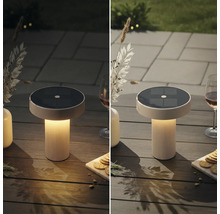Moderní solární stolní lampa s rýhovaným podstavcem na zahradním stole, srovnání při denním světle a za soumraku s teplým světlem.